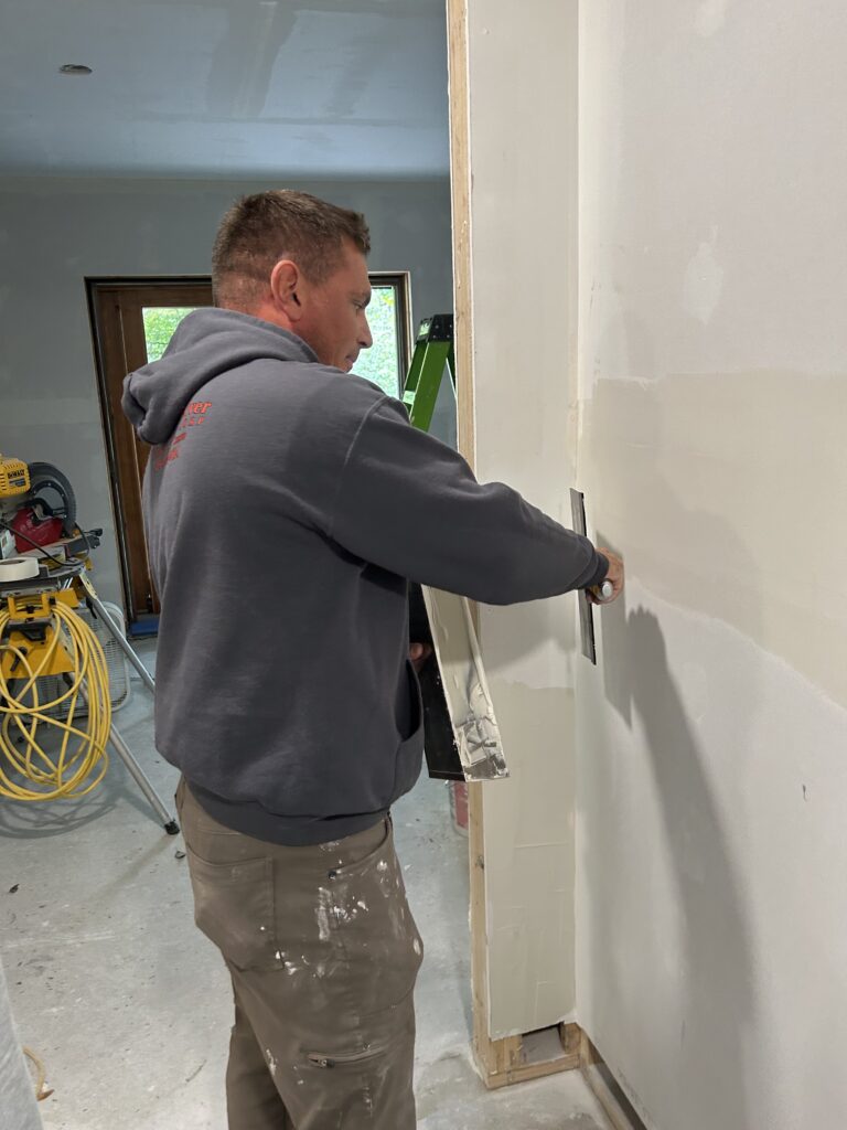 Cherokee River team member works on drywall, showing how homes are improved during remodeling or basement finishing projects.